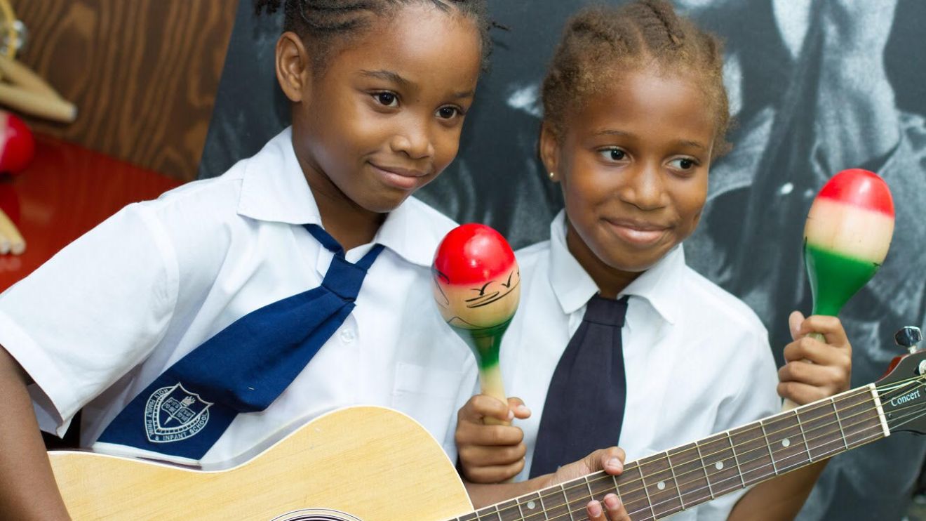Two young children playing with a guitar and maracas