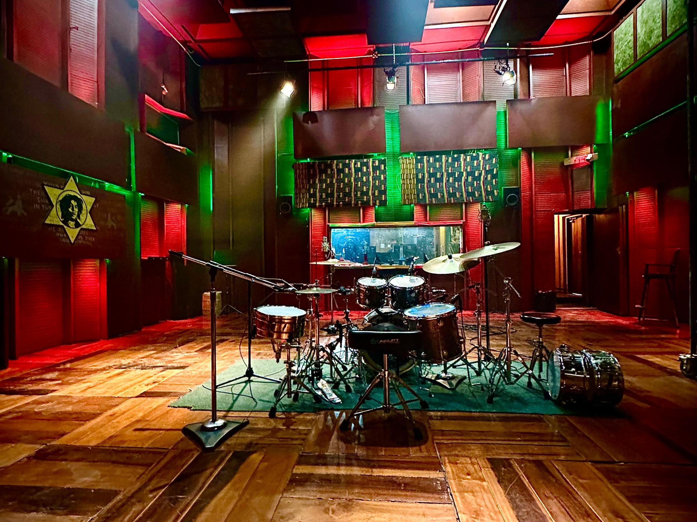 Empty recording studio with drum kit and wood panel flooring.